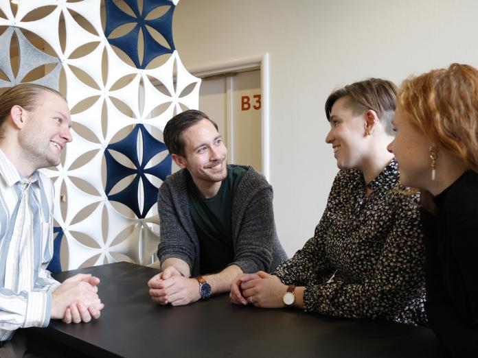 fire personer rundt om et bord som snakker